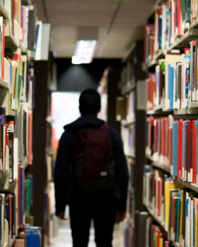 A high school student walking through a library