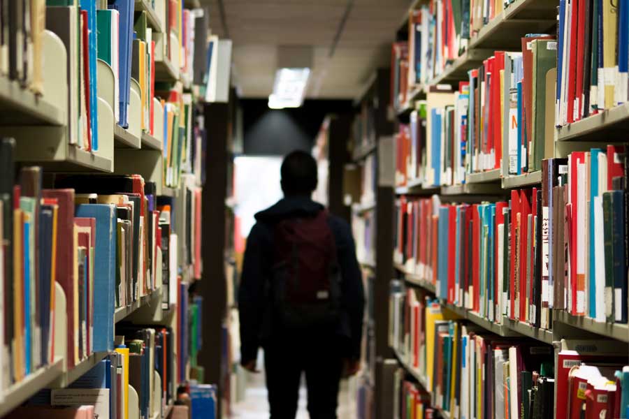 A high school student walking through a library